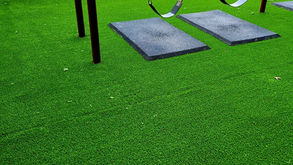 Artificial turf playground surface installed under outdoor play equipment
